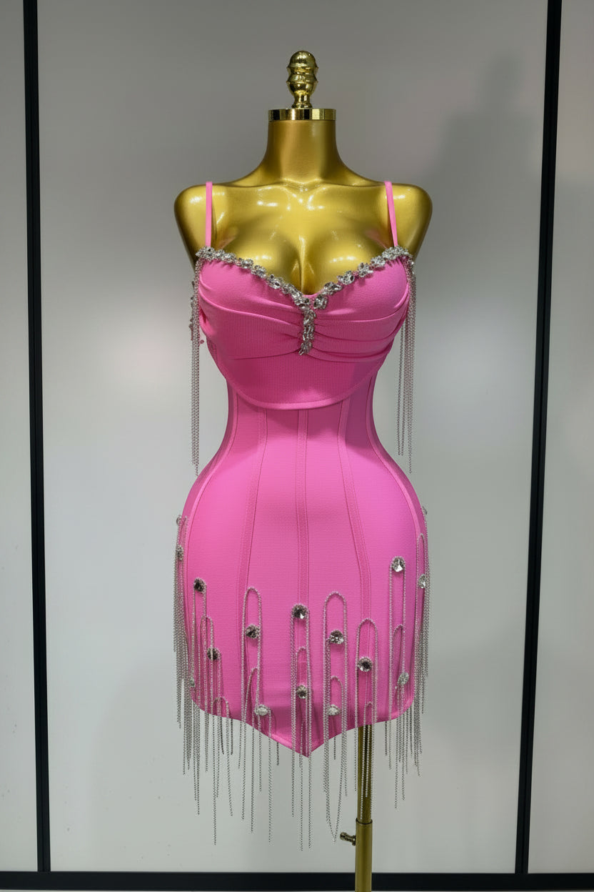 Pink dress with fringe and embellishments on a gold mannequin against a plain background