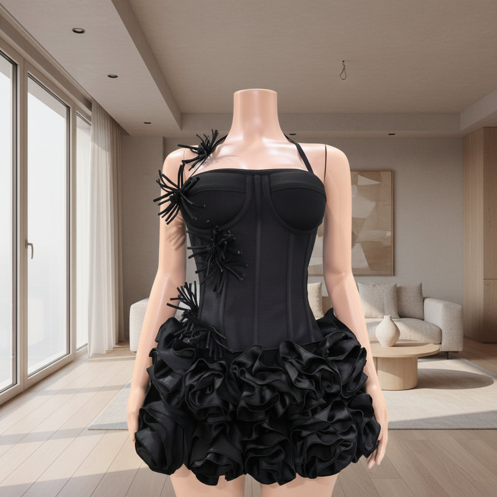 Black dress with floral details on a mannequin against a gray wall.