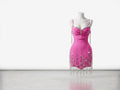 Pink dress with fringe details on a mannequin against a white background